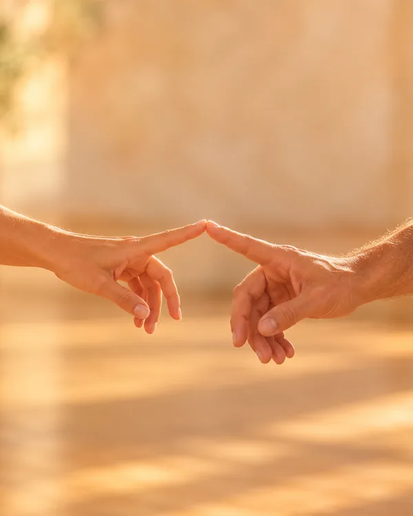 שתי ידיים נפגשות בקצות האצבעות באור חם